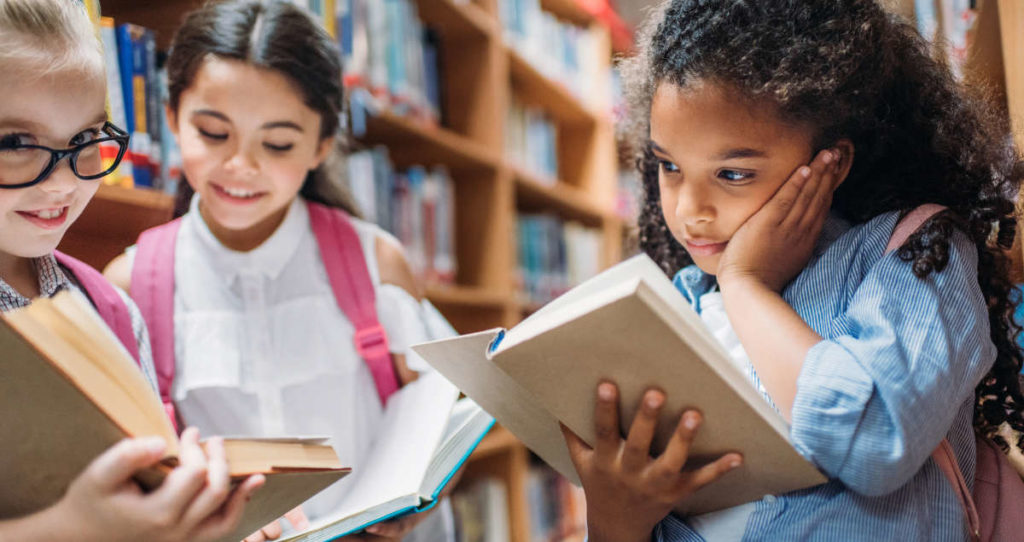 escolares leyendo libros en la biblioteca