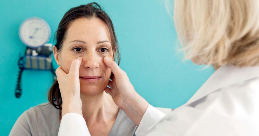 Médica examinando a mujer hispana para ver si tiene inflamación de los senos paranasales.