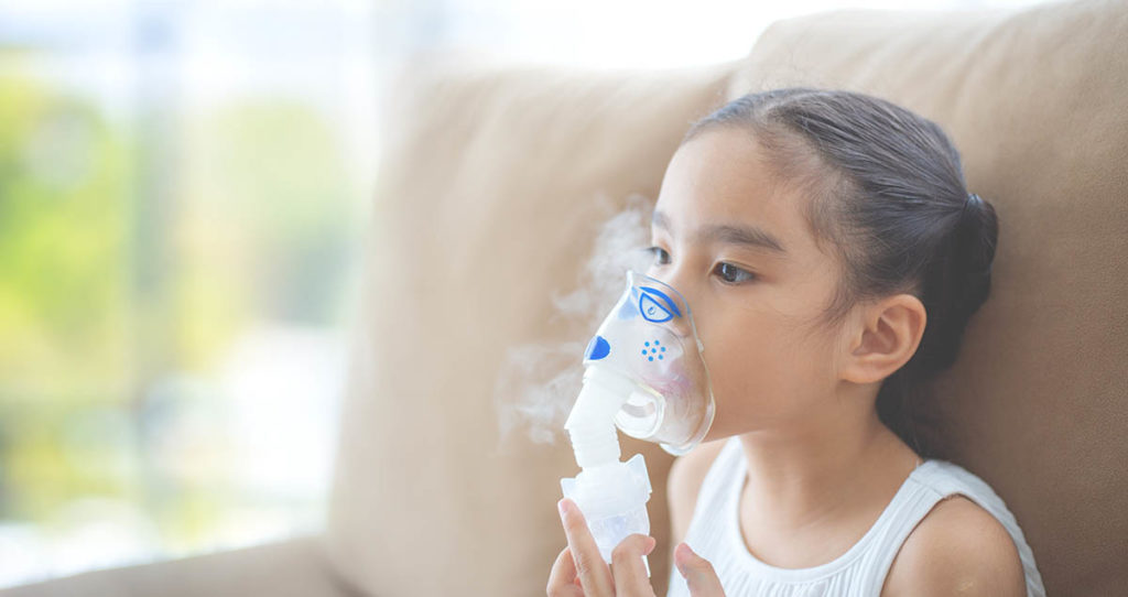 Joven asiática usando un nebulizador