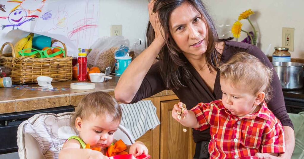 Cuidador inquieto sentado a la mesa con niños pequeños.