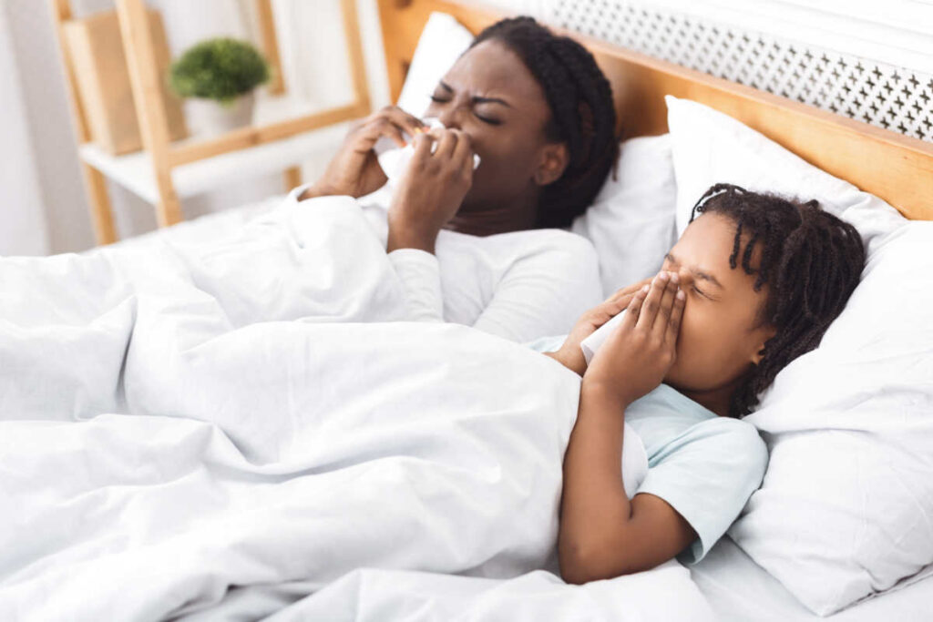 Foto de una madre y su hijo en la cama con rinitis alérgica