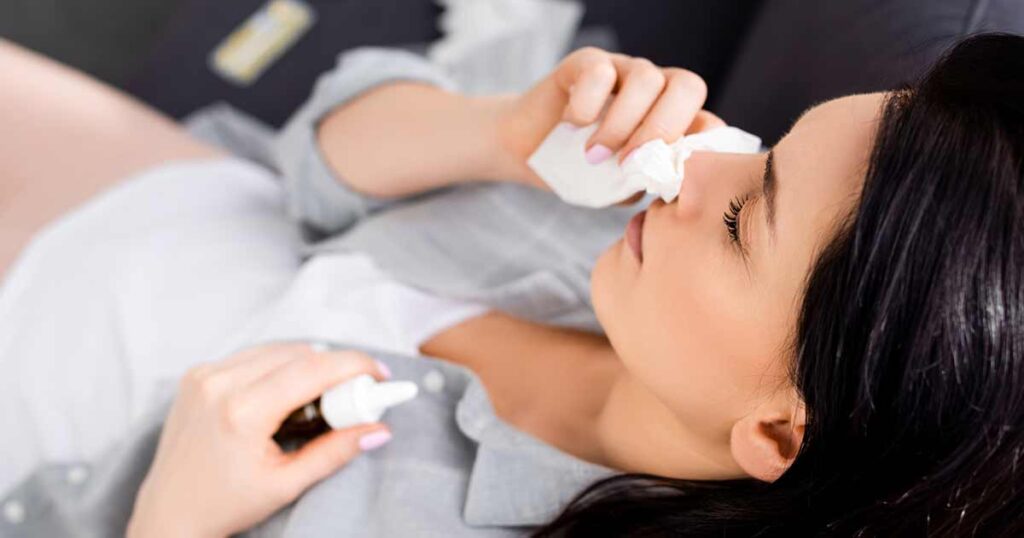 Mujer que usa spray nasal para alergias.