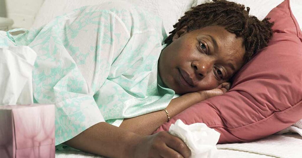 Foto de una mujer en cama por gripe.