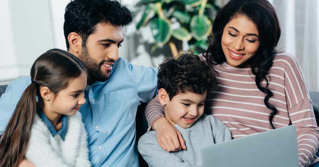 Familia hispana mirando una computadora portátil juntos.