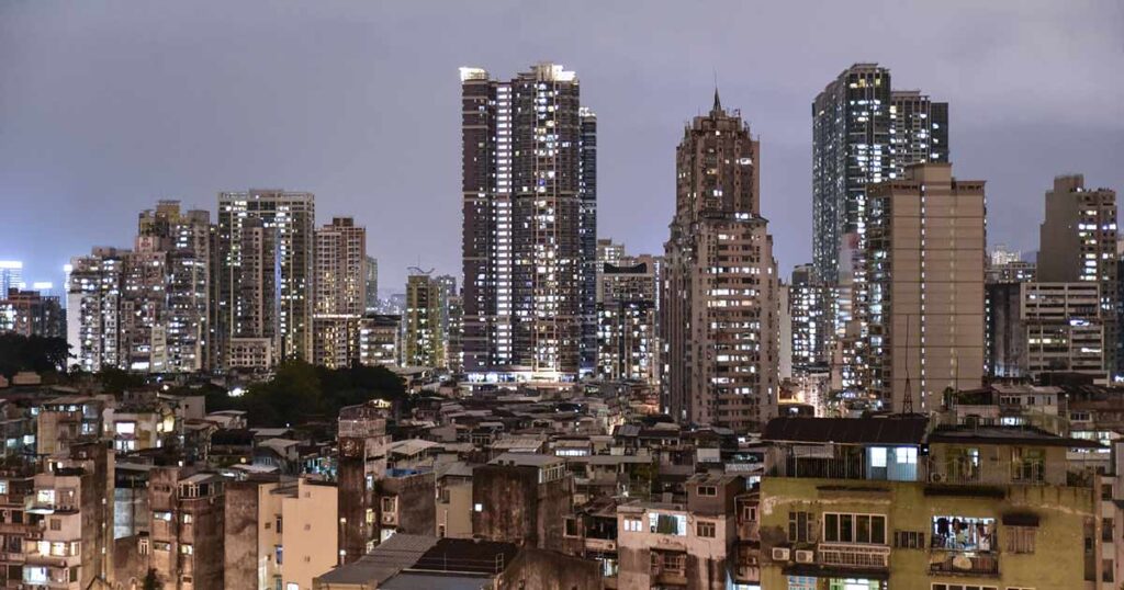 Foto nocturna de edificios que representan la riqueza con una barriada adelante, que representa a la clase trabajadora.
