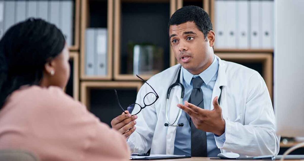Médico joven de raza negra hablando con su paciente.