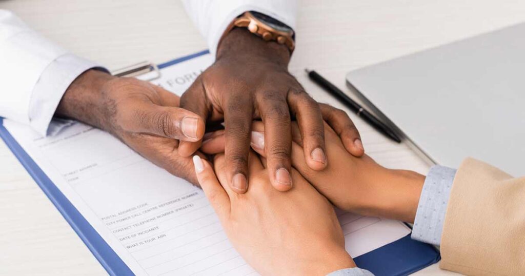 Un médico muestra su apoyo durante un momento estresante dándole la mano al paciente